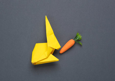 Plastic miniature carrot on dark gray background. Minimal, conceptual still life, creative layout
