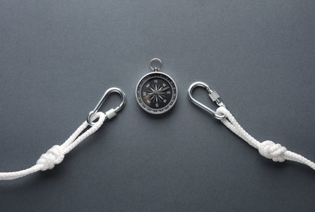 Carabiners with ropes and compass on dark background. Tourism, mountaineering, outdoor activities