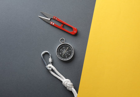 Carabiners with ropes and compass, scissors on yellow gray background. Tourism, mountaineering, outdoor activitiesの写真素材