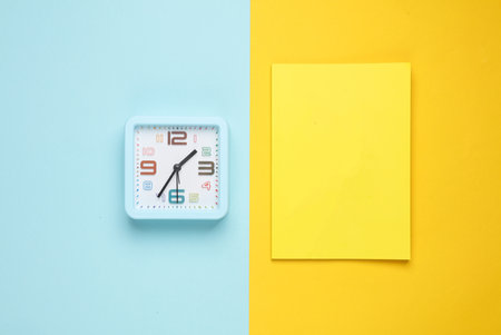 Notepad with clock on colorful pastel background. Top view