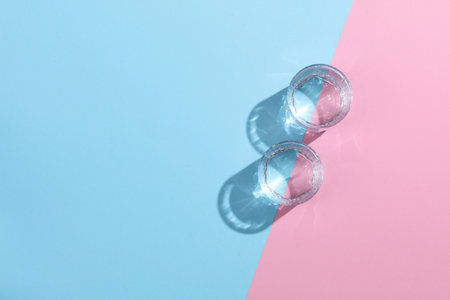 Glasses of water with reflection and shadow on pink blue pastel background. Minimalism. Top viewの写真素材