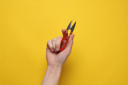 Hand holding Fishing or tailor scissors on yellow backgroundの写真素材