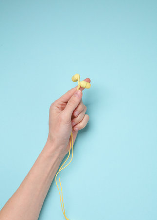 Hand holding wired headphones on blue background. Music loverの写真素材
