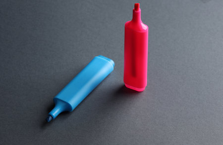 Blue and pink markers on dark background