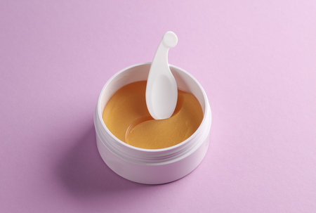 Jar with golden eye patches on purple background. Beauty conceptの写真素材