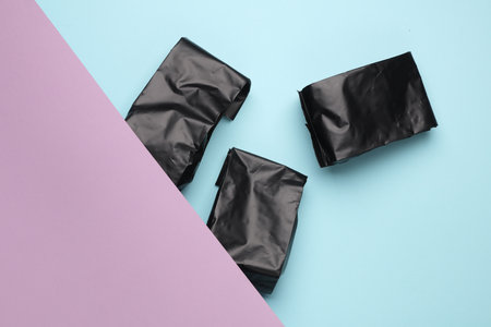 Black plastic product packaging bags on pastel backgroundの写真素材