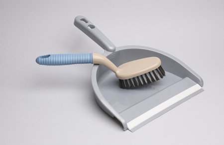 Dustpan and brush for cleaning on a gray background