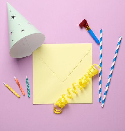 Festive birthday accessories with envelope on a pink background.の写真素材