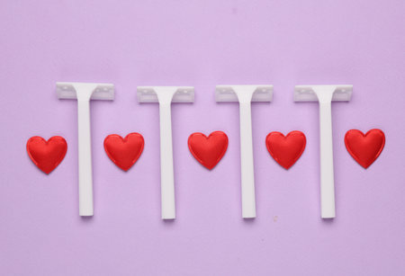Hearts and razors on purple background. Beauty concept. Top view