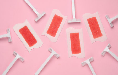 Wax strips for depilation and razors on pink background. Top viewの写真素材