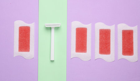 Wax strips for depilation and razor on pastel background. Minimalism beauty still life. Top viewの写真素材
