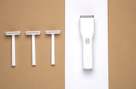 Clipper and razors on beige white background. Minimalism beauty still life