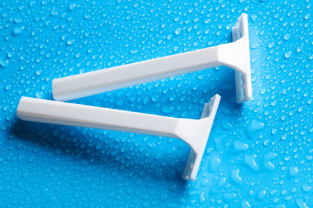 White razors on a blue background with water drops. Beauty concept