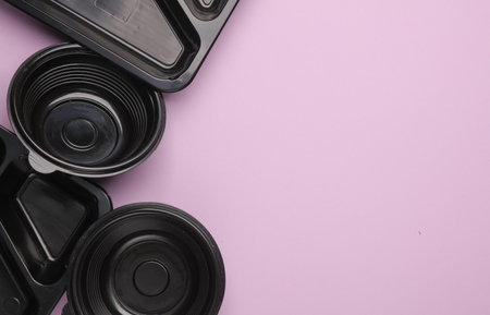 Disposable black plastic empty food containers on purple background. Top viewの写真素材