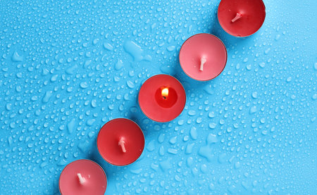 Tea aroma candles on a blue background with water dropsの写真素材