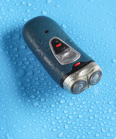 Electric shaver on blue background with water dropsの写真素材