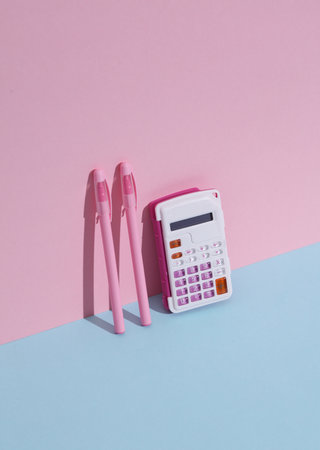 Calculator with pens on a blue-pink background with shadow. Business, education concept. Creative...