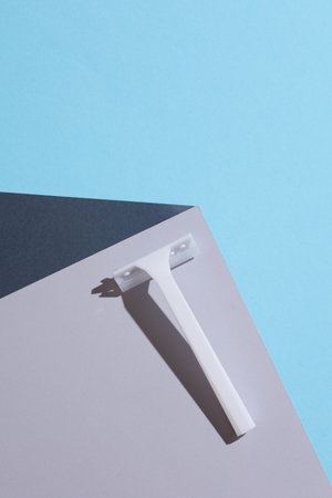 White razor on the corner of gray cube. Optical geometric illusion. Creative layout. Minimalism....