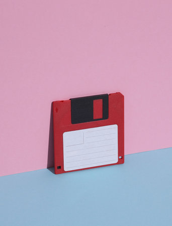 Red Floppy disk on a pink blue background. Retro 80s. Outdated technology. Creative layout, minimalism, trendy minimal still lifeの写真素材
