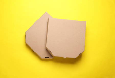 Two empty craft cardboard pizza boxes on yellow background. Template for design. Top viewの写真素材