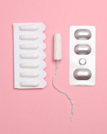 Vaginal suppositories, a tampon and a blister of pills on a pink background. Women Healthの写真素材