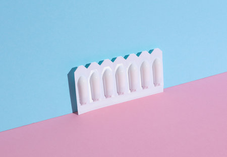 Blisters of vaginal suppositories on a pink blue background. Creative layout