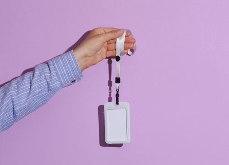 Man's hand in shirt holding id badge on purple background with shadowの写真素材
