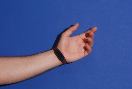 Male hand with a smart bracelet on a blue backgroundの写真素材