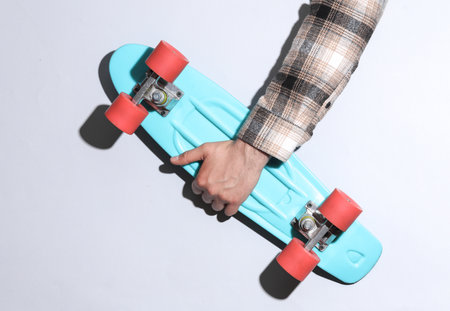 Man's hand in shirt holding penny board on gray background with shadowの写真素材
