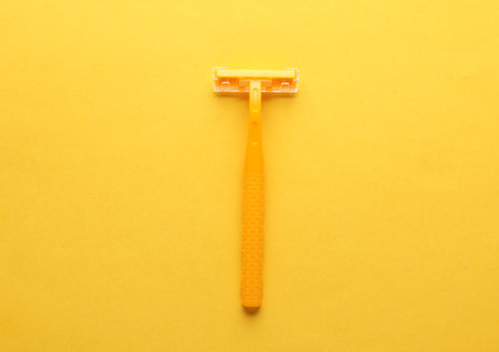 Yellow razor on a yellow background. Top viewの写真素材