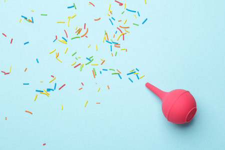 Enema with sprinkles on blue background. Minimal party concept