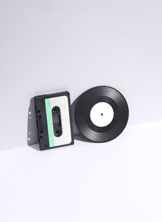 Retro 80s audio cassette and vinyl record on white background with shadow. Music lover. Creative...