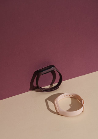 Smart bracelet with interchangeable silicone bracelets on a colored background with a shadow. Creative layoutの写真素材