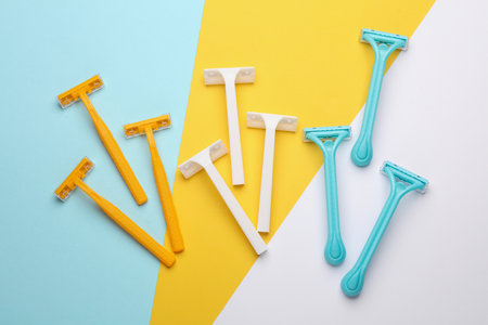 Set of plastic razors of different colors on three colored backgroundの写真素材