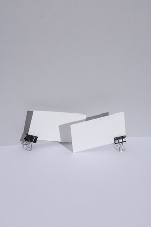White business cards with paper clips on a white background with shadow. Creative layout. Minimal business mockupの写真素材
