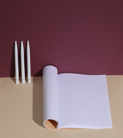 Open notebook with white blank sheets with pens on burgundy beige background. Education, business layoutの写真素材