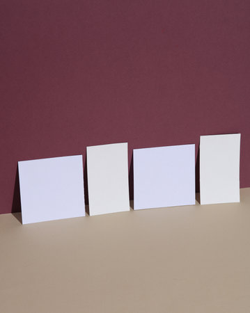 Square white memo papers and business cards on beige burgundy background with shadow. Creative layoutの写真素材