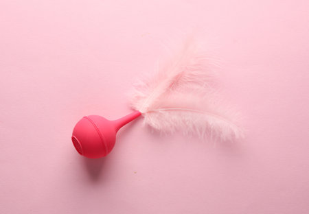 Pink enema with feathers on a pink background. Minimalismの写真素材