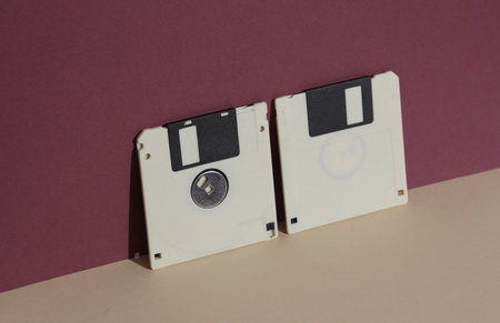 Retro 80s floppy disks on burgundy background with shadow. Creative layout, minimalism