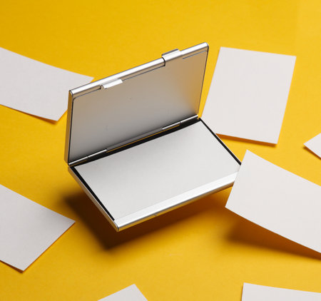 Metal box business card holder with business cards on yellow backgroundの写真素材