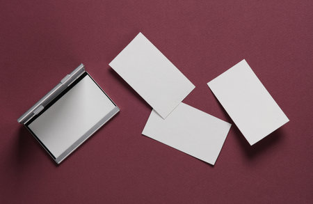 Metal box business card holder with business cards on burgundy background. Top viewの写真素材