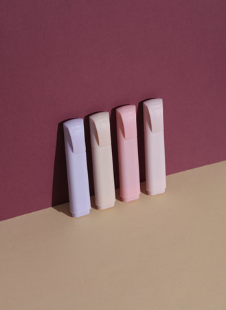 Colored markers on beige burgundy background with shadow. Creative layout