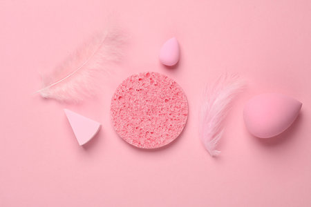 Make-up sponge, cosmetic beauty blenders with feathers on pink background. Top view. Flat layの写真素材
