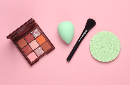 Make-up puff and sponge for removing makeup, eye shadow palette, brush on a pink background. Beauty productsの写真素材