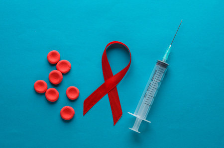 Syringe and red hiv, aids awareness ribbon, Red blood cells on blue backgroundの写真素材