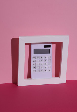 Calculator in white frame on pink background with shadow. Creative layout, minimalismの写真素材