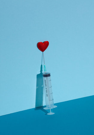 Syringe with heart on a blue background. Creative love or medicine conceptの写真素材
