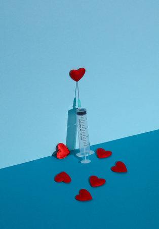 Syringe with hearts on a blue background. Creative love or medicine conceptの写真素材