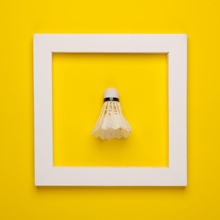 Shuttlecock in white frame on yellow background. Creative layout. Minimalism
