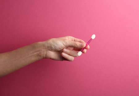 Applicator for makeup in female hand on pink backgroundの写真素材